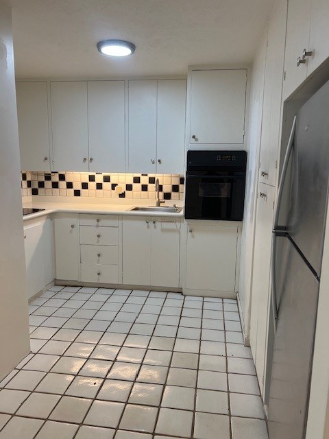 A kitchen with white cabinets and a black and white checkered backsplash.